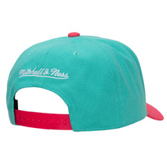 A turquoise and pink snapback cap shown from the back, featuring white embroidered 'Mitchell & Ness' branding on the side, a turquoise crown, a pink adjustable strap, and a pink button on top.