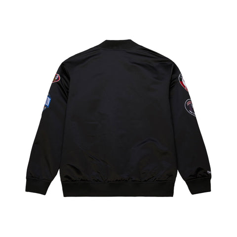 Black bomber jacket with patches on the back against a white background